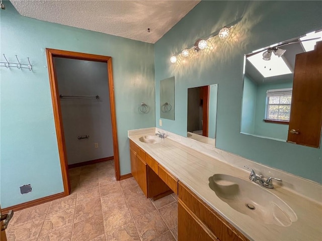 full bath featuring double vanity, a textured ceiling, baseboards, and a sink