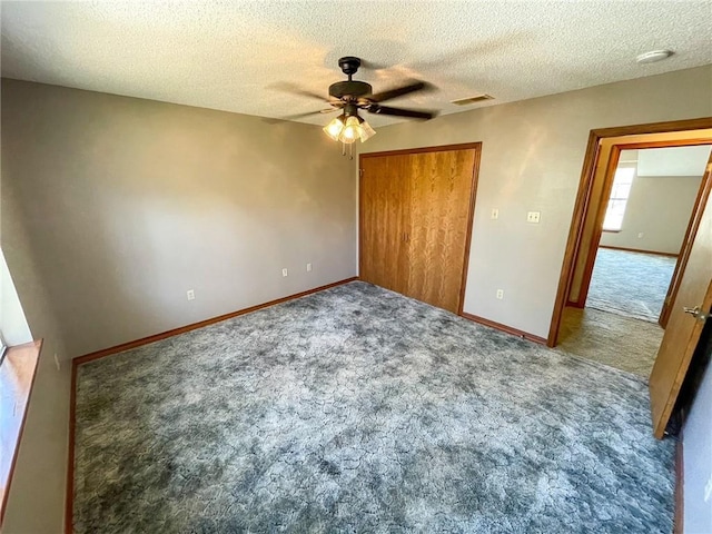 unfurnished bedroom with visible vents, a textured ceiling, a closet, carpet floors, and baseboards