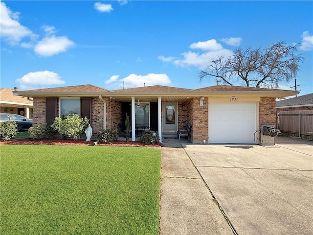 ranch-style home featuring a front yard, concrete driveway, brick siding, and an attached garage