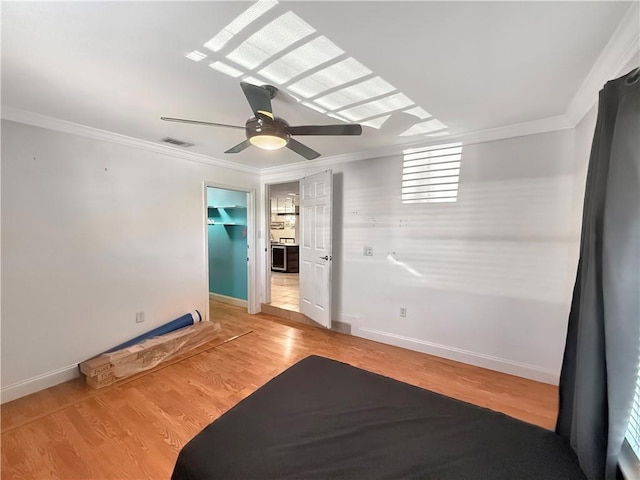 interior space featuring visible vents, baseboards, ceiling fan, ornamental molding, and light wood-style flooring