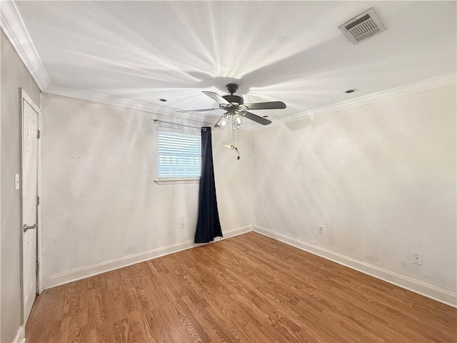 unfurnished room with baseboards, wood finished floors, visible vents, and ornamental molding