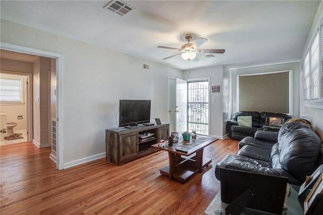 living area featuring baseboards, visible vents, and light wood finished floors