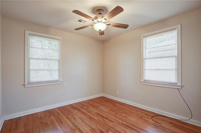 spare room featuring light wood-style floors, baseboards, a wealth of natural light, and ceiling fan