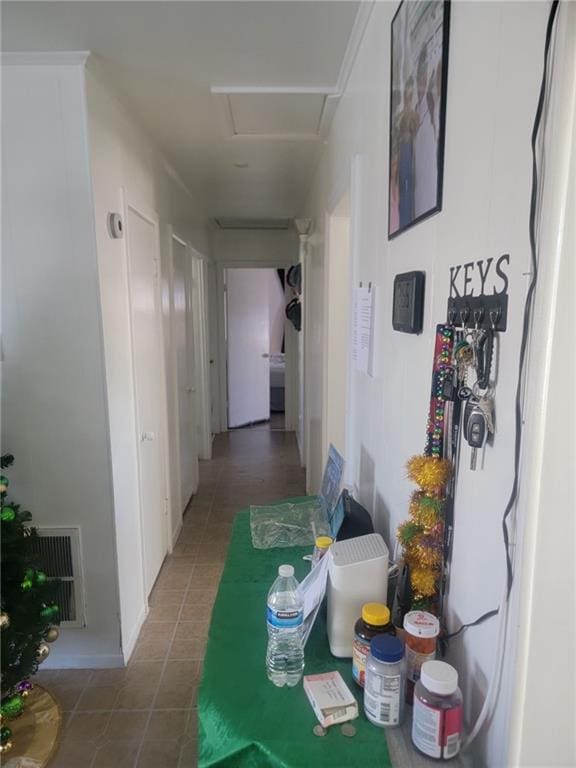 corridor with attic access, tile patterned flooring, and visible vents