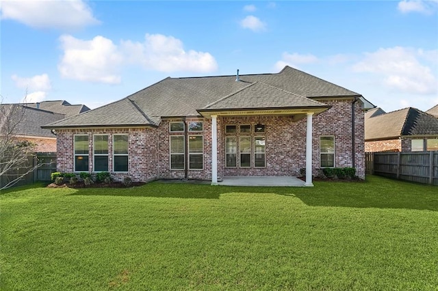 rear view of property with a yard, a fenced backyard, brick siding, and roof with shingles