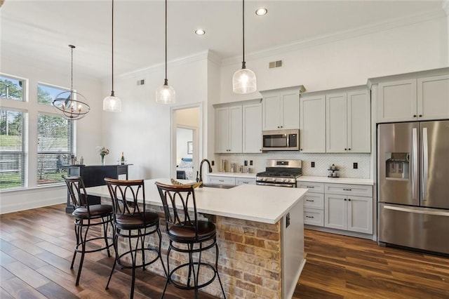 kitchen with dark wood-type flooring, tasteful backsplash, appliances with stainless steel finishes, and a breakfast bar area