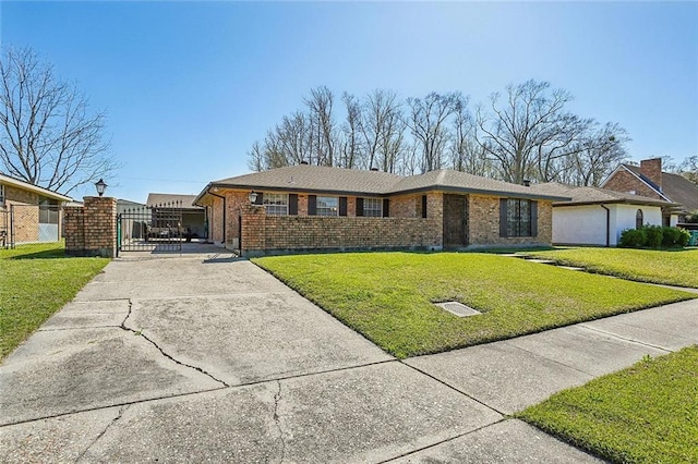 view of front of house with brick siding, concrete driveway, a front lawn, and a gate