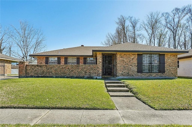 ranch-style house featuring a front lawn, brick siding, and a shingled roof