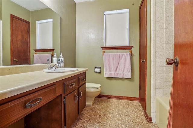 bathroom with toilet, vanity, and baseboards