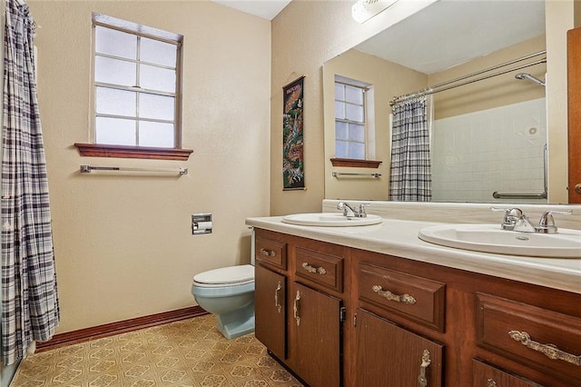 bathroom featuring a sink, baseboards, toilet, and double vanity