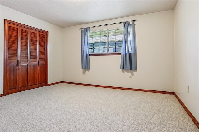 unfurnished bedroom with baseboards, carpet floors, and a closet