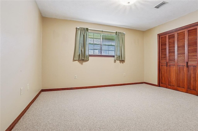 unfurnished bedroom featuring carpet flooring, baseboards, visible vents, and a closet