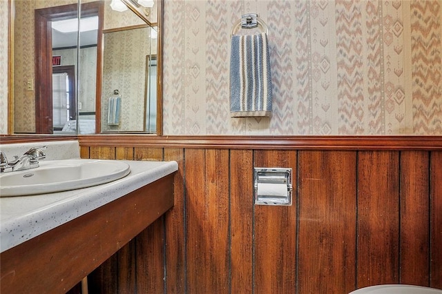 bathroom with wainscoting, wallpapered walls, and vanity