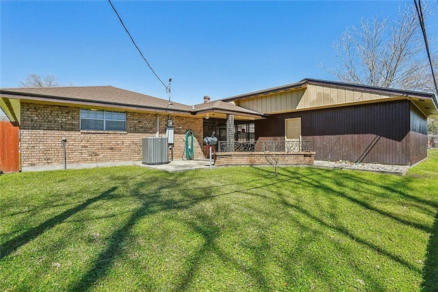 back of house featuring brick siding, central air condition unit, and a lawn