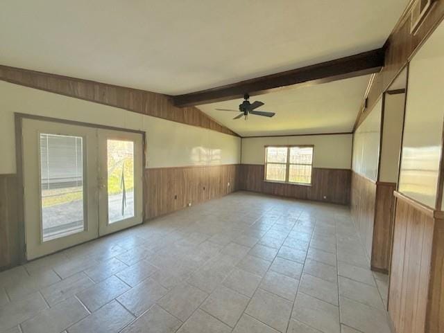 empty room with vaulted ceiling with beams, a ceiling fan, a wainscoted wall, and wood walls