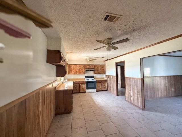 kitchen with white range with electric stovetop, visible vents, wainscoting, and under cabinet range hood