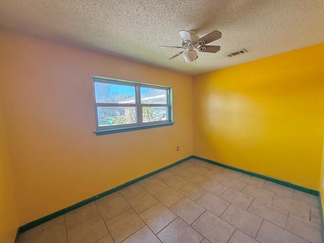 unfurnished room featuring visible vents, a textured ceiling, baseboards, and ceiling fan