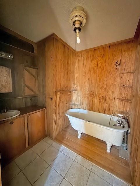 bathroom featuring a freestanding tub, wooden walls, vanity, and tile patterned flooring