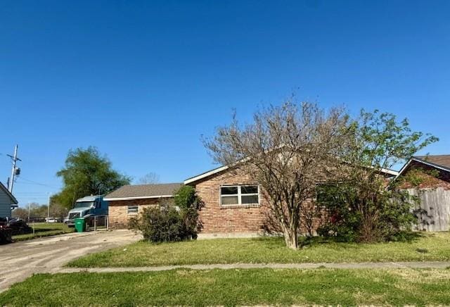 view of front of house with brick siding, a front yard, and fence