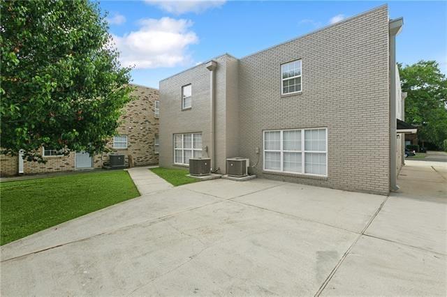 rear view of house featuring a yard, a patio, brick siding, and central AC unit