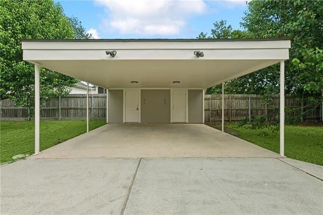 view of car parking with a carport, concrete driveway, and fence