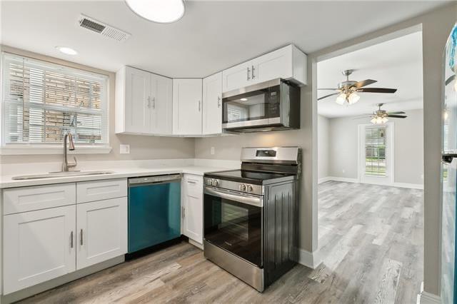 kitchen featuring a sink, visible vents, white cabinetry, and stainless steel appliances