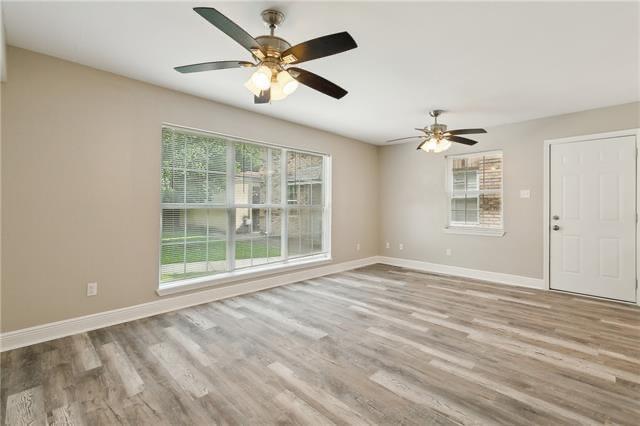 unfurnished room featuring a wealth of natural light, baseboards, and wood finished floors