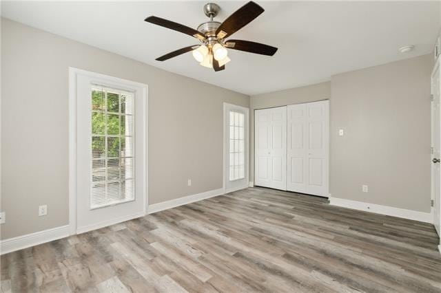 unfurnished bedroom with wood finished floors, baseboards, a closet, and ceiling fan