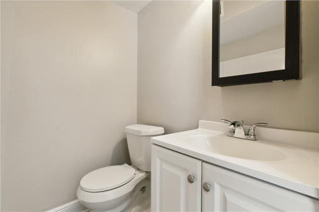 bathroom with baseboards, toilet, and vanity