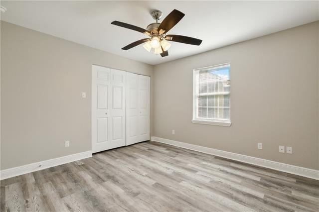 unfurnished bedroom featuring a ceiling fan, wood finished floors, baseboards, and a closet