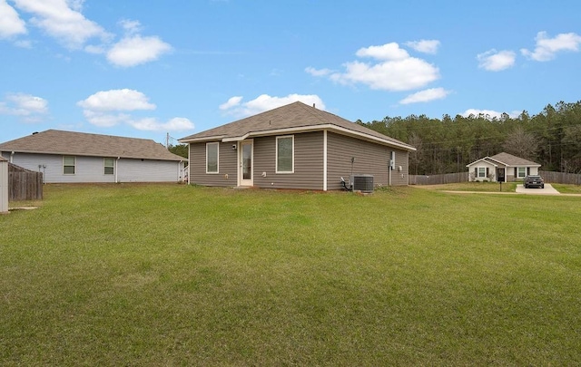 rear view of house featuring central AC unit, a yard, and fence