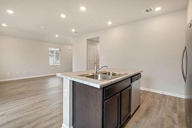 kitchen featuring visible vents, a sink, dark brown cabinetry, light wood-style flooring, and stainless steel dishwasher