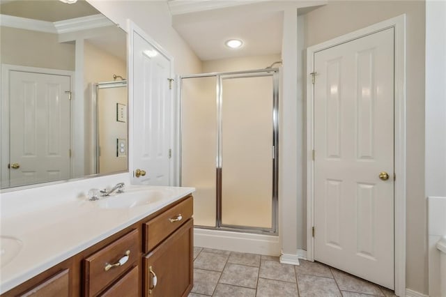 bathroom with double vanity, a stall shower, a sink, crown molding, and tile patterned floors