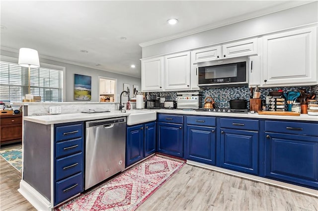 kitchen featuring blue cabinetry, light countertops, appliances with stainless steel finishes, a peninsula, and a sink