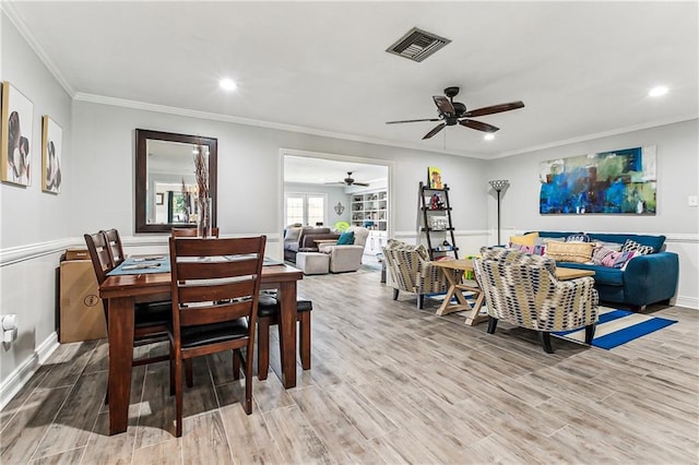 dining space featuring visible vents, light wood finished floors, and ornamental molding