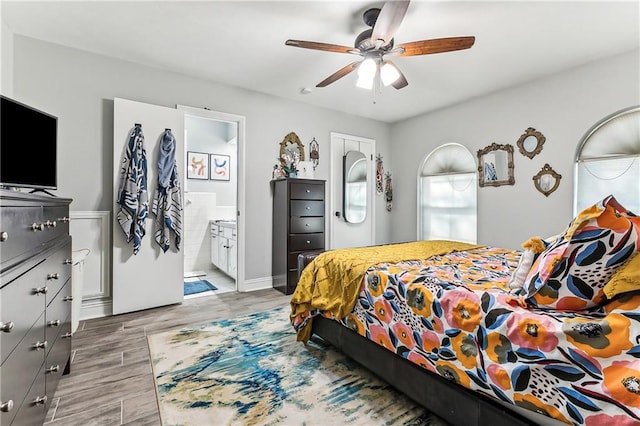 bedroom featuring light wood-type flooring, ensuite bath, and a ceiling fan