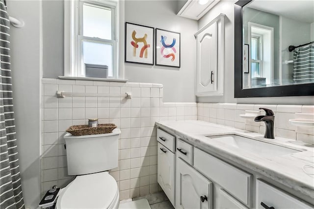 full bathroom with a wainscoted wall, toilet, curtained shower, tile walls, and vanity