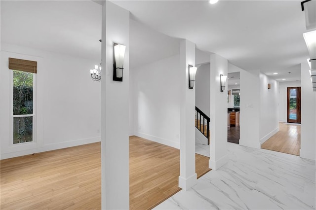 interior space with wood finished floors, baseboards, a chandelier, and stairs