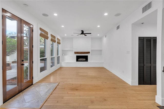 interior space with visible vents, baseboards, light wood-style floors, and a fireplace with raised hearth