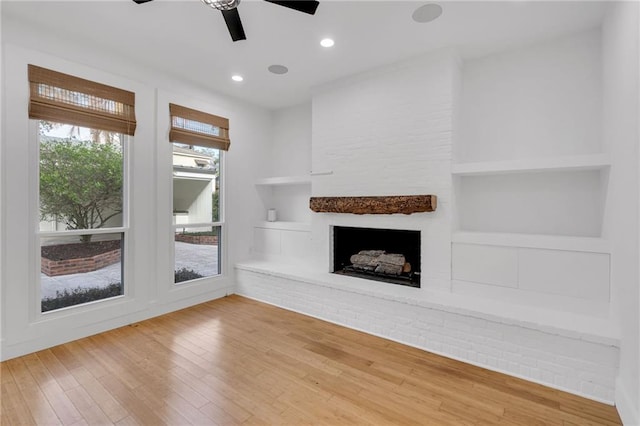 unfurnished living room featuring built in shelves, a ceiling fan, wood finished floors, recessed lighting, and a fireplace