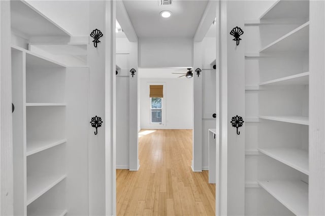 hallway featuring visible vents, built in shelves, and wood finished floors