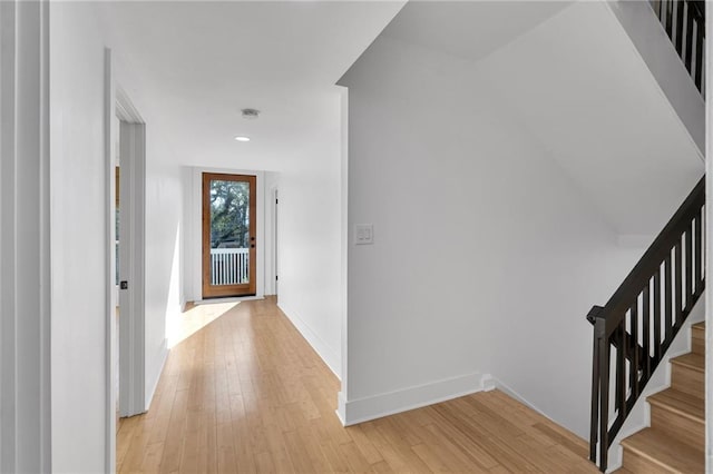 hall featuring baseboards, light wood-style flooring, and stairs