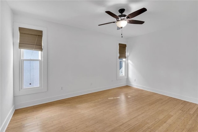 spare room featuring ceiling fan, baseboards, and light wood-style floors