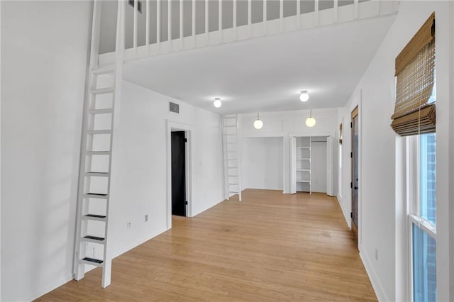 unfurnished room with visible vents, light wood-type flooring, baseboards, and built in features