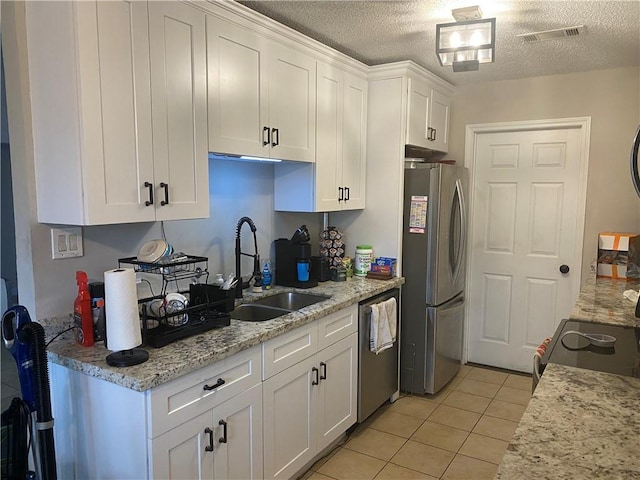 kitchen with visible vents, light tile patterned floors, white cabinets, stainless steel appliances, and a sink