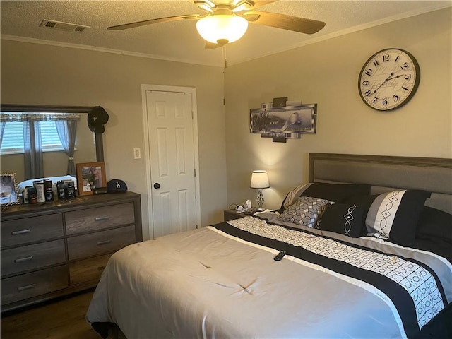 bedroom with visible vents, a ceiling fan, a textured ceiling, crown molding, and dark wood-style flooring