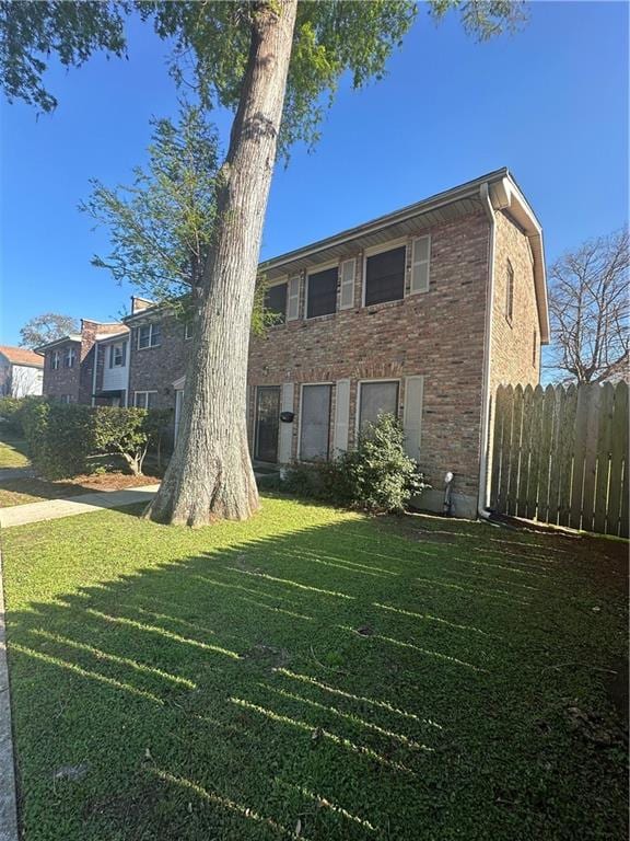 view of front of property featuring a front yard, fence, and brick siding