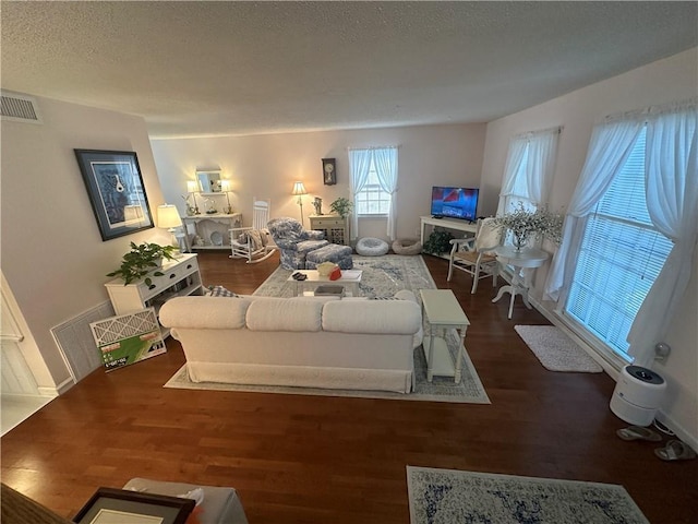 living room with visible vents, a textured ceiling, and wood finished floors