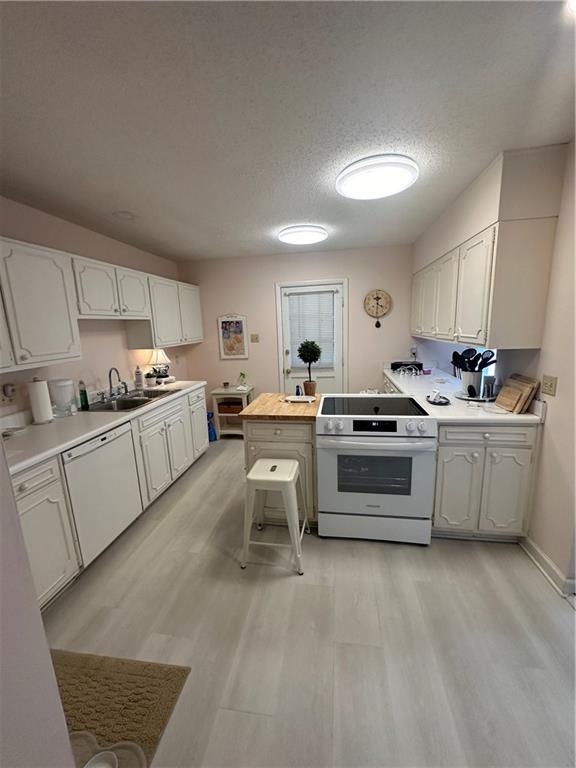 kitchen featuring white appliances, light countertops, light wood-style floors, and a sink