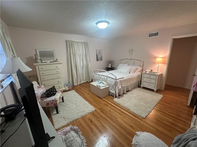 bedroom with visible vents, a textured ceiling, and light wood-type flooring